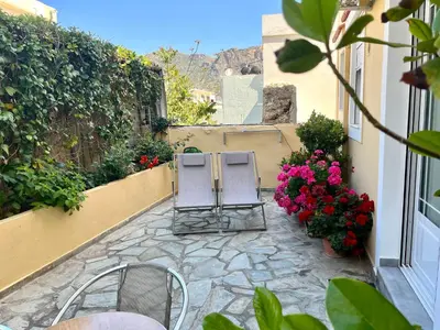 a patio with two chairs and flowers on a building at Harbour Studios And Apartments in Palaiochóra