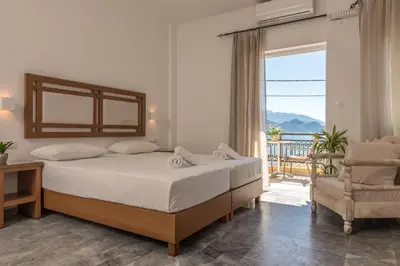 a bedroom with a bed and a chair and a window at Harbour Studios And Apartments in Palaiochóra
