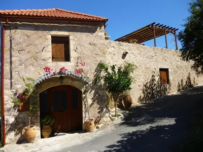 a stone building with a door and flowers on it at Charmante maison crétoise à Embrosneros in Embrósneros