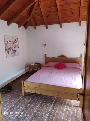a bedroom with a wooden bed with pink sheets at Charmante maison crétoise à Embrosneros in Embrósneros