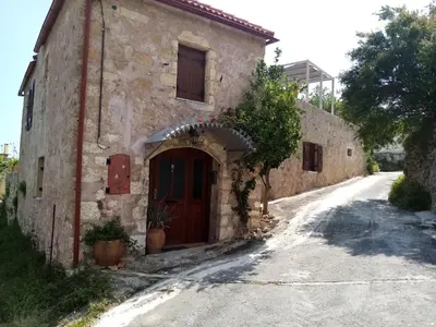 an old stone building with a door on a road at Charmante maison crétoise à Embrosneros in Embrósneros