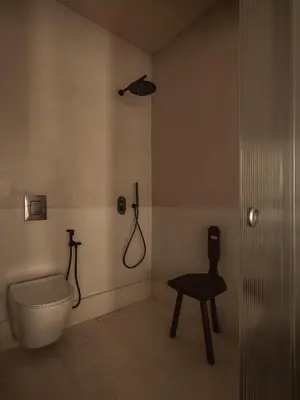 a bathroom with a toilet and a chair in it at Aisha Hotel in Chania Town