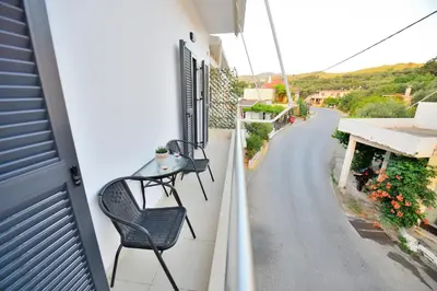 a balcony with two chairs and a street at Anatoli Apartment in Kissamos