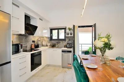 a kitchen with white cabinets and a wooden table at Anatoli Apartment in Kissamos