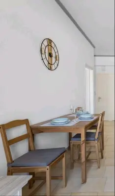 a dining room table with chairs and a clock on the wall at Seafront Apartment in Chania 7 in Chania Town