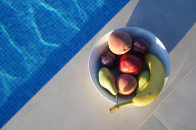 a bowl of fruit next to a swimming pool at Afea Villas in Plataniás
