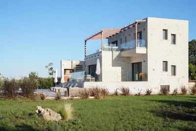 a large stone building with a lawn in front of it at Afea Villas in Plataniás