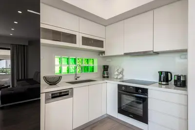 a kitchen with white cabinets and a black oven at Modern Dream Apartment in Plataniás