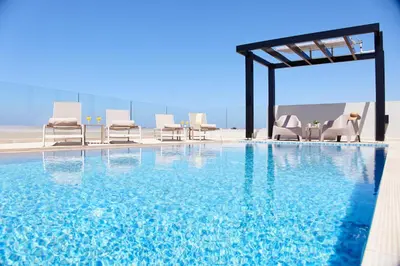 a large swimming pool with chairs at Beach Sand Villas - Beachfront Roof Pool Seaviews in Pírgos Psilonérou