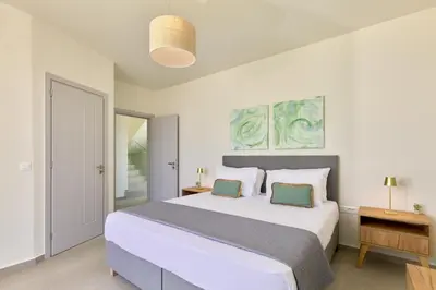 a bedroom with a large white bed with two green pillows at Beach Sand Villas - Beachfront Roof Pool Seaviews in Pírgos Psilonérou