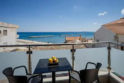a table on a balcony with a view of the ocean at Iria Sea View Room in Kolymvari