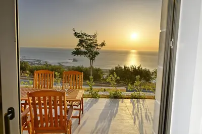 a table and chairs on a patio with a view of the ocean at Rosmari Studios in Falasarna