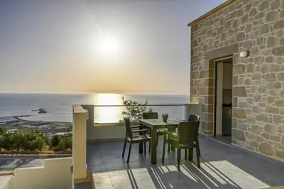 a patio with a table and chairs and the ocean at Rosmari Studios in Falasarna