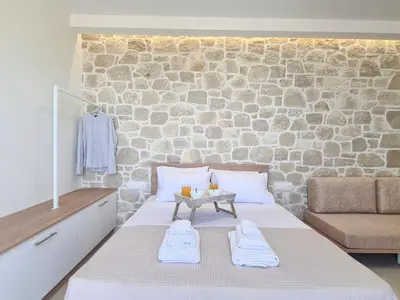 a bedroom with a bed with a stone wall at Rosmari Studios in Falasarna