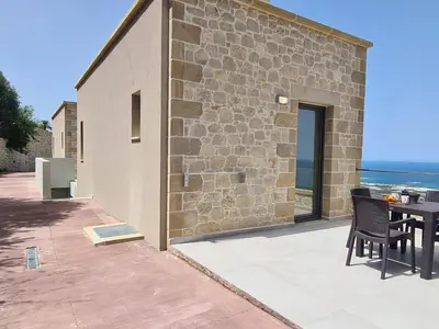 a stone building with a table and chairs on a patio at Studios Rosmari in Áyioi Pándes