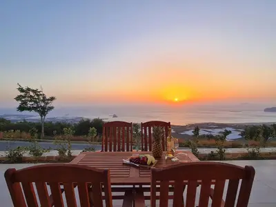 a wooden table with chairs and a sunset in the background at Studios Rosmari in Áyioi Pándes