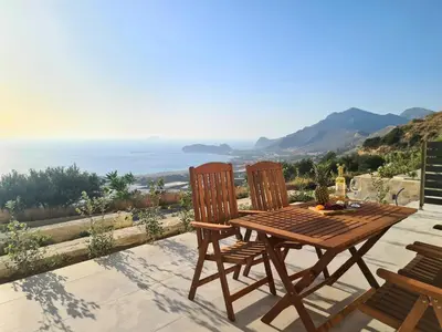 a wooden table and chairs on a patio with a view of the ocean at Studios Rosmari in Áyioi Pándes