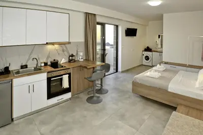 a bedroom with a bed and a kitchen with a sink at Studios Rosmari in Áyioi Pándes