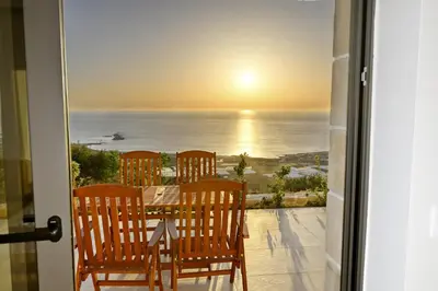 a table and chairs on a balcony with a view of the ocean at Studios Rosmari in Áyioi Pándes