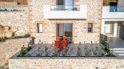 a brick house with orange chairs in front of it at Studios Rosmari in Áyioi Pándes