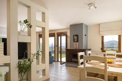 a living room with a table and chairs and a fireplace at Olive Garden Villa 5 min from Golden Beach in Galatás