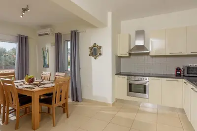 a kitchen with a table and chairs and a kitchen with white cabinets at Aloni Grove Retreat in Chania Town