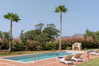 a swimming pool with lounge chairs and palm trees at Aloni Grove Retreat in Chania Town