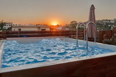 a hot tub filled with water with a sunset in the background at Thearia villa II private heated hydromassage pool in Souda
