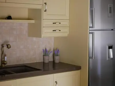 a kitchen with white cabinets and a stainless steel refrigerator at Christina's Villa with sea view in Daratso