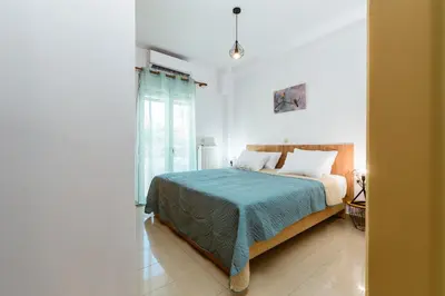a bedroom with a bed with a blue blanket at Ferenikis apartment in Chania Town