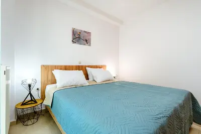 a bedroom with a large bed with a blue blanket at Ferenikis apartment in Chania Town