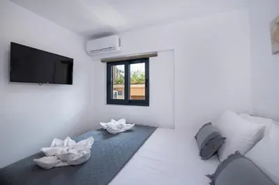 a white living room with a tv and a couch at Halepa Apartment's in Chania in Chania Town
