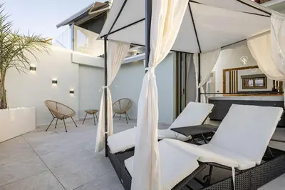 a patio with white chairs and a pool table at Beachfront luxury suite in Kalyves