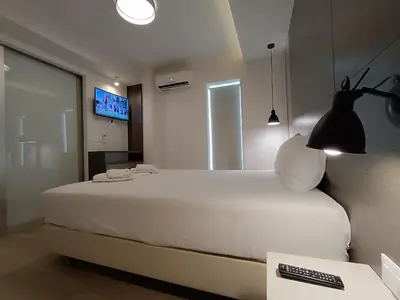 a bedroom with a white bed and a television at Sandy Suite 1 in Agia Marina Nea Kydonias