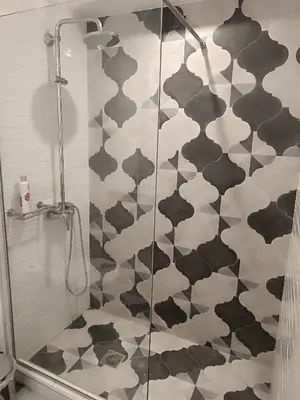 a bathroom with a shower with black and white tiles at Sandy Suite 1 in Agia Marina Nea Kydonias