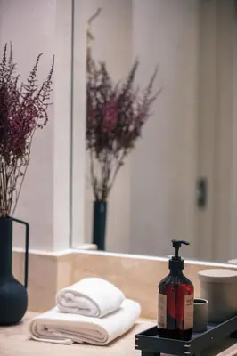 a bathroom counter with a bottle of soap and towels at Sea Path I Chania City Center luxury Suites in Chania Town