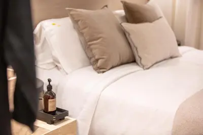 a white bed with a bottle of wine on a night stand at Sea Path II Chania city Center luxury Suites in Chania Town