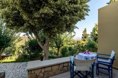 a table and chairs on a patio with a tree at Heliopetra studios, small village near beaches in Douliana