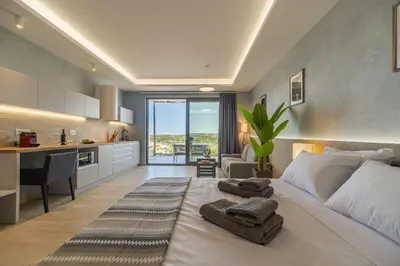 a bedroom with a large white bed and a kitchen at Amour Relax Hotel in Almirida