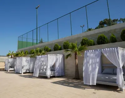 a row of white curtains and trees in front of a building at Amour Relax Hotel in Almirida
