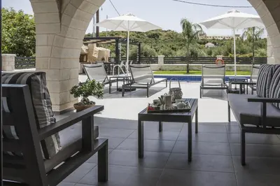 a patio with chairs and a table and a pool at Villa-Azalea in Almirida
