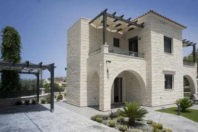 a stone house with an archway in a yard at Villa-Azalea in Almirida