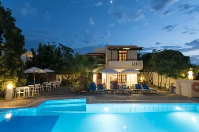 a villa with a swimming pool at night at Proimos Maisonnettes in Plataniás