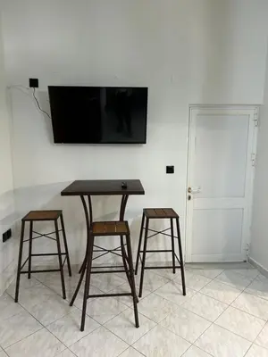 a table with two stools and a television on a wall at Marias Apartment in Chania Town