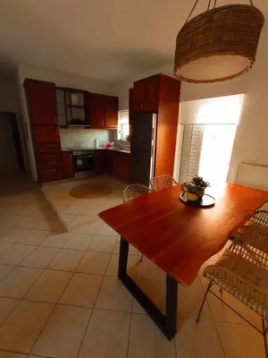 a living room with a wooden table and a kitchen at Sonema Seaside Apt in Chania Town