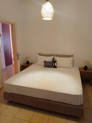 a bedroom with a large white bed with a chandelier at Sonema Seaside Apt in Chania Town