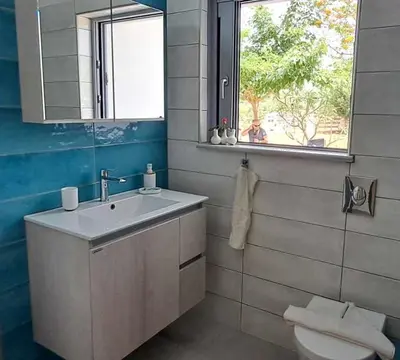 a bathroom with a sink and a toilet and a window at MariAdni Garden House in Kissamos