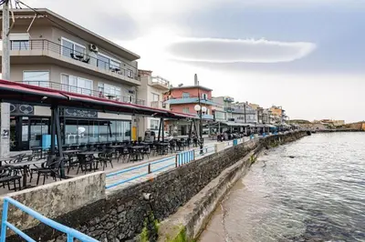 a restaurant with tables and chairs next to the water at The Sandgate Elegant studio, Chania Seaside in Chania Town