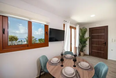a dining room with a wooden table and chairs at Iasmos in Sfakiá