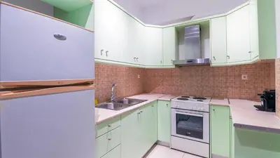 a kitchen with green cabinets and a white refrigerator at Paleochora Central Apartments in Palaiochóra